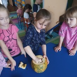 trzy dziewczynki przy stoliku jedna dziewczynka wydrąża dynię
