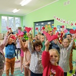 Grupa dzieci tańczy trzymając papierowe serca