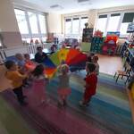 dzieci tańczą trzymając wielokolorową chustę animacyjną