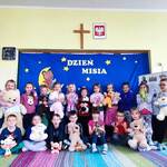 zdjęcie grupowe dzieci z misiami. Z tylu niebieskie tło, miś na księżycu i napis dzień misia