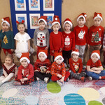 Mikołajki - dzieci ubrane na czerwono w czapkach Mikołaja pozują do zdjęcia grupowego