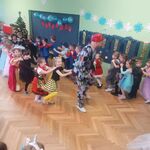 dzieci w przebraniach uformoway pociąg za mężczyzną w kolorowym stroju i czerwonym kapeluszu.jpg