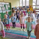 Dzieci stoją na dywanie i czekają na rozpoczęcie zabaw ruchowych 