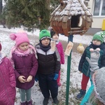 grupa dzieci ustawiona przy drewnianym karmniku.jpg