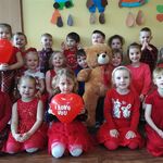 Grupa dzieci pozuje do zdjęcia dziecko trzyma balon inne mają dużego misia.
