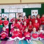 grupa ubranych na czerwono dzieci pozuje do zdjęcia w rękach  balony w kształcie serca