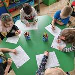 Grupa dzieci rysuje kredkami przy stoliku
