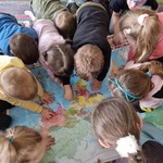 Grupa dzieci na dywanie ogląda mapę świata.