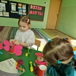 Dwie dziewczynki siedzą przy stoliku i ozdabiają swoje papierowe motyle.