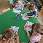 Grupa dzieci koloruje motyla przy stolikach