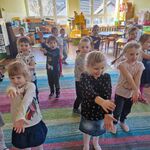 Dzieci stoją na dywanie_ ręce  wyprostowane trzymają przed sobą_ naśladują dziób bociana