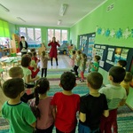 Grupa dzieci patrzy na kobietę jak pokazuje ruchy do piosenki.