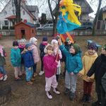 dwójka uśmiechniętych dzieci trzyma kukłę marzanny w niebieskiej sukience
