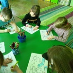 Kilkoro dzieci przy stoliku uzupełnia kartę pracy dotyczacą obiegu wody w przyrodzie
