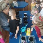 dzieci obserwujące pracę działkowca przy wysiewaniu kwiatów.
