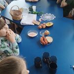 dzieci przy stole na którym leżą pokarmy przygotowane do włożenia do koszyczka.