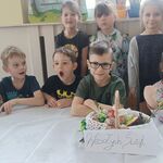 grupa uśmiechniętych dzieci ze święconka_ ustawiony napis Wesołych Świąt.