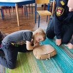 chłopiec uczy się na manekinie nasłuchiwać czy poszkodowany oddycha.