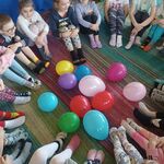 dzieci siedzące w kręgu z wystawionymi skarpetkami -każda inna. W środku polorowe balony.