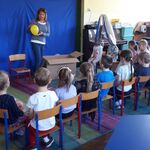 pani trzymająca żółty balon z literą_ wokół dzieci.