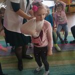 pielęgniarka demponstruje na dziewczynce jak nałozyć temblak.
