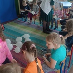 dzieci siedzą na krzesłach_ pielęgniarka rozdaje kolorowanki.