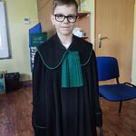 chłopiec w okularach w czarnej todze z żabotem