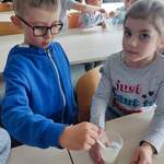 dziewczynka i chłopiec mieszają jogurt w kubeczku.