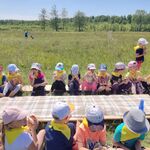 dzieci zgromadzone wokół piknikowego stołu jedzą posiłek