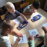 czworo dzieci siedzi przy stoliku i koloruje wizerunek sowy stworzony z kólek.jpg