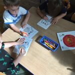 dzieci siedzą przy stoliku i kolorują wizerunek sowy stworzony z kólek.jpg