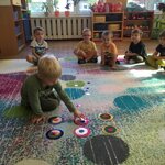 chłopiec na dywanie odtwarza koliste wzory_ w tle siedzi 5 dzieci.jpg