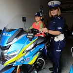 Komenda 7 Chłopiec siedzi na motocyklu policyjnym obok policjantki.jpg