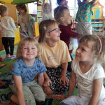 Dzieci siedzą pod chustą Klanzy z naelektryzowanymi włosami.