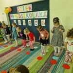 3 Dzieci ustawione w szeregu skaczą na kolorowe papierowe kółka.jpg
