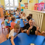 Dzień P-laka 8  Grupa dzieci degustuje ciastka przy stolikach.jpg