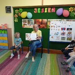 Mama siedzi obok córki i prezentuje ilustrację czytanej ksiązki.