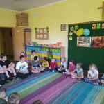 dzieci i uczniowie siedzą w kole na dywanie.