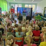 Aktor prezentuje makietę domu_ dzieci siedzą naprzeciwko.
