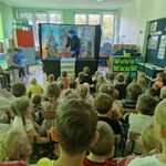 Aktor stoi za stołem_ w rękach trzyma samochód z pacynką lisa.
