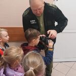 Funkcjonariusz Straży Granicznej pokazuje dzieciom_ jak korzystać z lornetki .