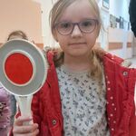 Dziewczynka trzyma w ręku tarczę do zatrzymywania pojazdów.
