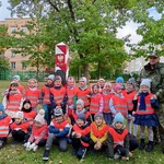 Grupa przedszkolaków pozuje przy słupie granicznym.