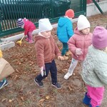 grupa dzieci stojących wsród liści.