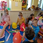 Dzieci przy stolikach przygotowują elementy do pracy plastycznej.