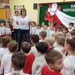 stojąca na środku kobieta i zgromadzone wokół niej dzieci
