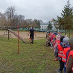 Grupa dzieci ogląda na podwórku tresurę psa.