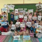 Grupa przedszkolaków prezentuje wykonane kolorowanki.