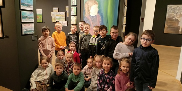 Grupa dzieci pozuje w galerii obrazów.