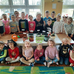 Zdjęcie grupowe dzieci z panią Bogusią - ogrodniczką oraz posianymi i posadzonymi roślinami